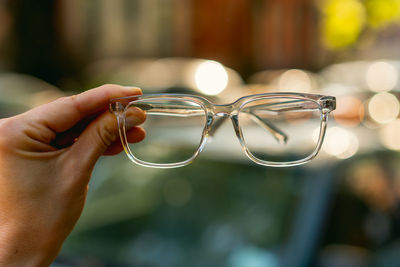 Close-up of hand holding eyeglasses against blurred background