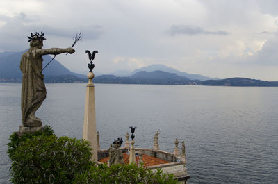 Statue by sea against sky