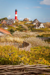 Lighthouse by building against sky