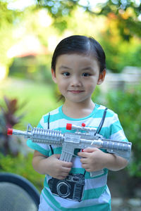 Portrait of cute girl holding toy handgun