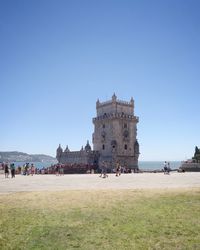 People at seaside against clear blue sky