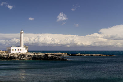 Lighthouse by sea against sky