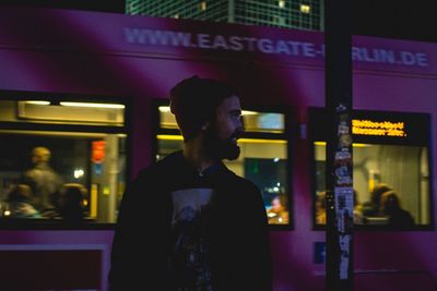 Smiling young man standing against cable car at night