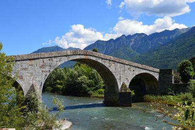 Arch bridge over river against sky