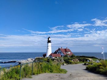 Lighthouse by sea against sky