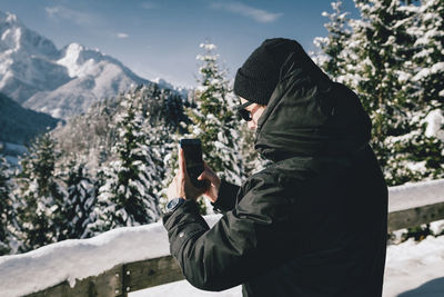 Side view of man photographing with smart phone during winter