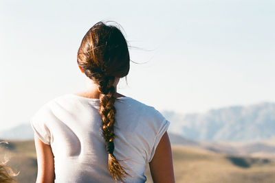 Rear view of woman with braided hair standing against clear sky