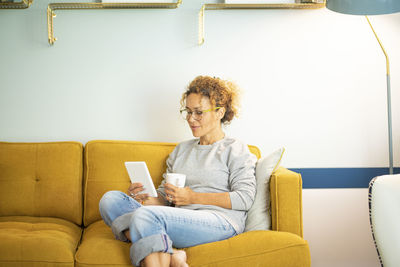 Young woman using laptop while sitting on sofa at home