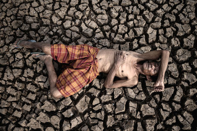 Full length of senior man with lying on cracked land