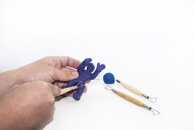 Close-up of hand holding cigarette over white background