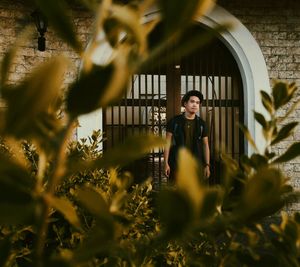 Young man looking away while standing at arch doorway