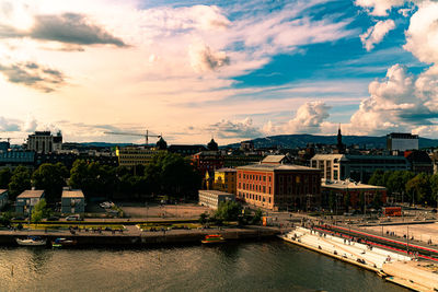 Bridge over river by buildings in city against sky