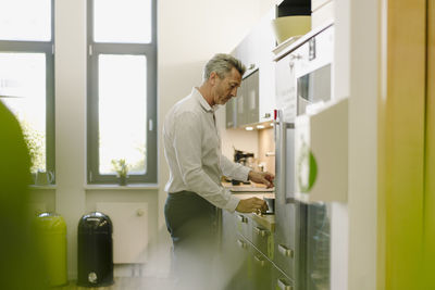 Man using coffee maker while standing at cafeteria