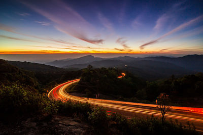 Light trails on road against sky at night