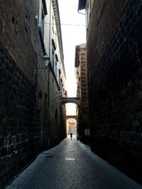 Rear view of people walking on footpath amidst buildings