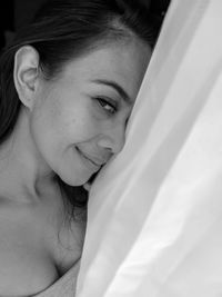 Close-up portrait of a smiling young woman lying on bed