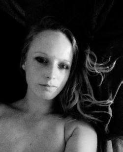 Close-up portrait of young woman against black background