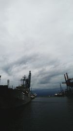 Boats in harbor against cloudy sky