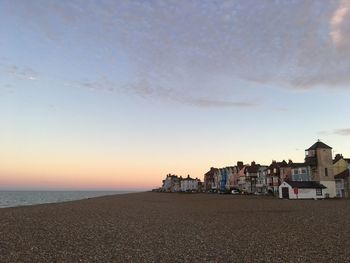 Buildings by sea against sky during sunset