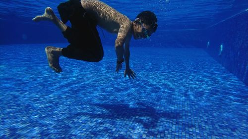 Full length of shirtless man swimming in pool