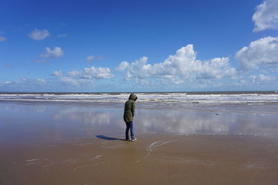 Rear view of woman standing at beach