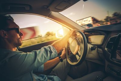 Side view of mid adult man driving car