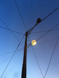 Low angle view of street lights against blue sky