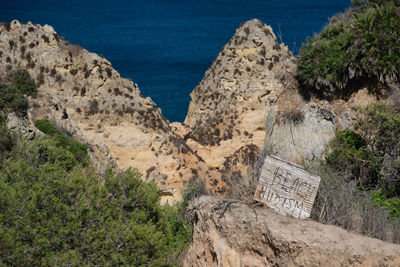 Beach nudism, rock formations by sea against sky