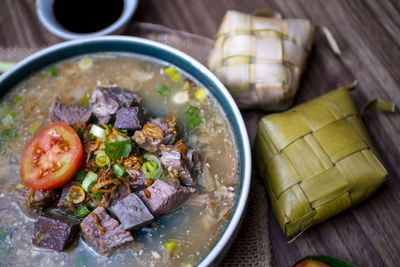 Coto makasar and ketupat, indonesian traditional food, taken with high angle view on table