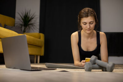 Young woman using phone while sitting on table