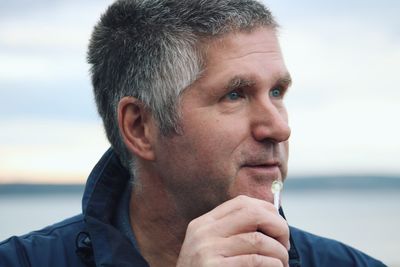 Close-up of mature man looking away against sea