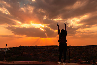 Girl backlit shot with sunset dramatic sky with sun beams with dark clouds at dusk