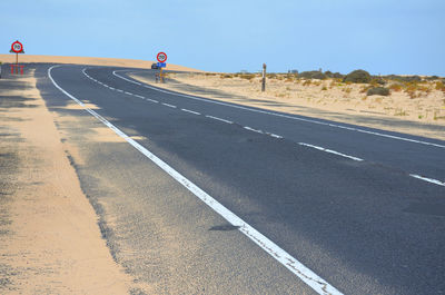 Empty road in city against clear sky