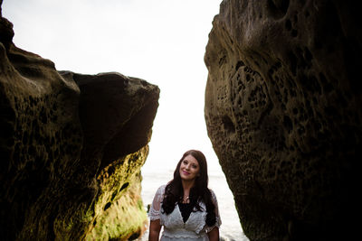 Portrait of woman standing on rock against sky