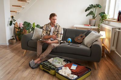 Young man using laptop while sitting on sofa at home