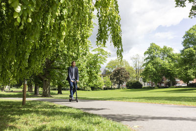 Businessman using e-scooter in a park
