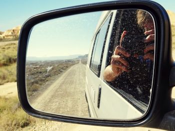 Reflection of man on side-view mirror