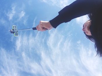High section of woman taking selfie against sky