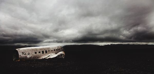 Abandoned airplane against cloudy sky