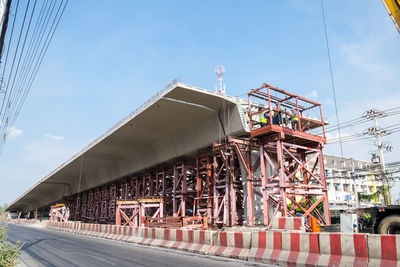 Low angle view of workers at construction site in city against sky