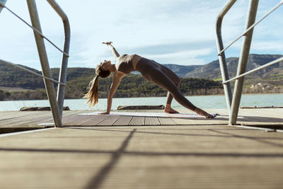 Woman practicing yoga on jetty