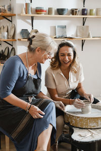 Teacher and student at pottery workshop learning to make bowls from clay. happy woman doing handmade