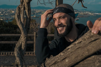 Bearded man smiling by tree trunk