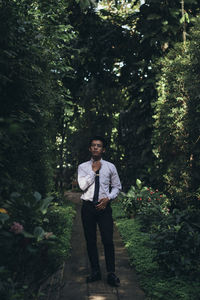 Portrait of young man standing against trees