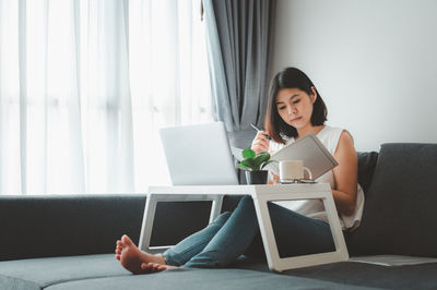 Woman working on sofa at home