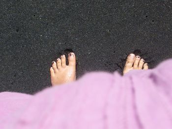 High angle view of woman feet on black sand