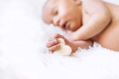 Baby holding heart shaped object sleeping at home