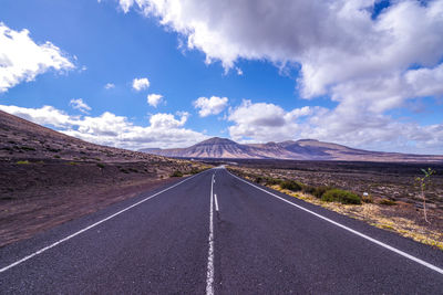 Empty road along landscape and mountains against sky