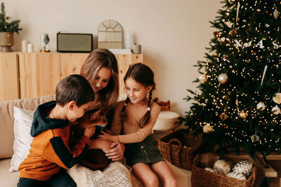 A family celebrates christmas holidays in winter at home. mom with teenage children in living room