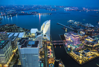 High angle view of illuminated buildings by river at night